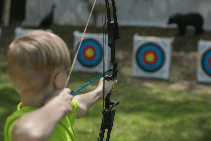 boy aiming bow and arrow at bullseye