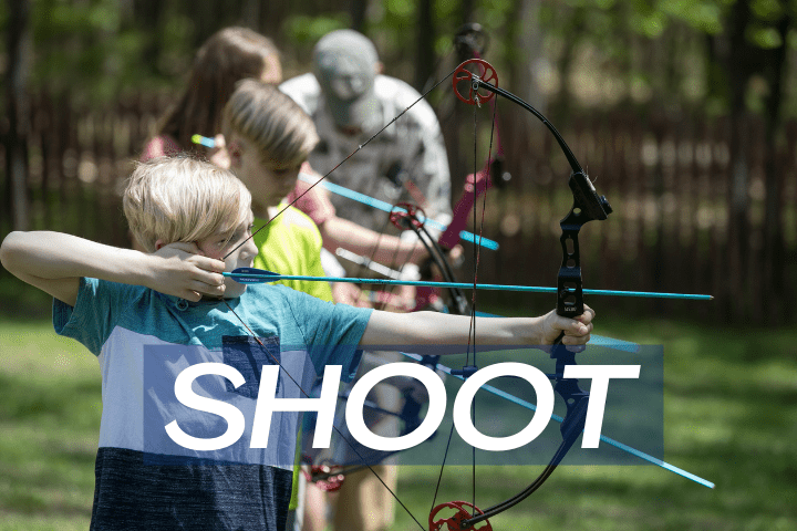 two boys and a girl in summer shooting bow and arrow
