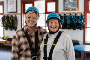 two ladies posing for photo wearing zip line harness