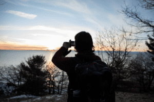 person taking photo of sunset over the lake at Muskegon State Park